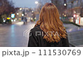 Rear plane. Pretty woman walking in black coat and light brown dress. 111530769