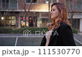 Medium lateral plane. Pretty woman walking in black coat and light brown dress. 111530770