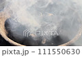 A close-up view of charcoal in a grill, flaming smoldering with wisps of light smoke rising. 111550630