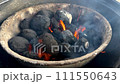 Charcoal grill with active orange flames and smoke in the wind. 111550643