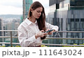 Woman businesswoman with a phone in hand typing a message on the roof of a building on the background of the big city skyscrapers and business center, business trip for work. 111643024