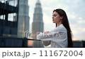 A woman stands on the roof of a high-rise building on the street and looks at the view of the city and high-rise buildings with a slight smile, a modern businesswoman 111672004
