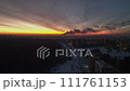 Aerial view of city at dusk, smoke rising from chimneys under red sky afterglow 111761153
