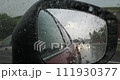 Close-up of a car side mirror covered with raindrops 111930377