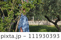 A steadicam shot capturing a woman walking in a garden and gently touching the rose bushes 111930393