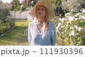 Close-up of a woman gently touching and examining the leaves of a plant in the garden 111930396