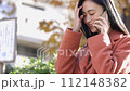 一位女士在公園的長椅上使用電腦打電話 112148382