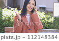 一位女士在公園的長椅上使用電腦打電話 112148384