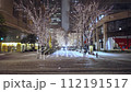 Snow falling in Tokyo at night, illumination of street trees, and cars passing by on the snowy road in Marunouchi 112191517