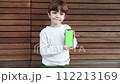 a toddler sits on a bench and looks on the phone with green screen 112213169