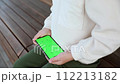 a toddler sits on a bench and rotates the green screen phone horizontal orientation 112213182