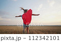 girl with the cloak. concept of a happy childhood and family for a child. a little girl in a superhero costume runs across a field, a red cape and a blue T-shirt, lifestyle sunset on the background 112342101