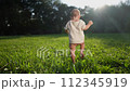 baby takes first steps in the park. happy family kid dream concept. son baby to walk takes the first steps in the park on green grass. baby lifestyle son taking first steps 112345919