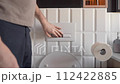 A man presses the flush button in the toilet. Daily morning sanitary and hygienic procedures when visiting the toilet. Home plumbing, sewerage and water supply are necessary for a comfortable life. 112422885