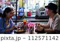 Young adult Asian man and woman in relationship enjoy eating and talking in the street food stall shop in Bangkok, Thailand. Couple backpacker eating street food. Southeast Asia tourism concept 112571142