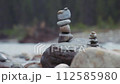 Balanced stones stacked on a big rock next to the river. Slow motion, close up. 112585980