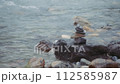 Stack of balanced stones near the flowing mountain river. Slow motion.  112585987