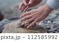 A woman making a balanced pyramid out of river stones. Slow motion.  112585992
