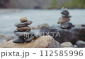 Two stacks of balanced stones near the mountain river. Slow motion, close up. 112585996