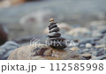 Cairns of balances stones near the river shore. Slow motion, close up.  112585998