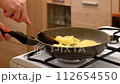Unrecognizable man flipping potato pancakes with spatula in frying pan 112654550