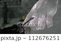 Closeup of ice sculptor hands cutting shaping two figures 112676251