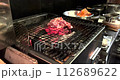 日本一家餐廳的廚房裡，一名廚師正在木炭上烤雞肉。 112689622