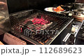 日本一家餐廳的廚房裡，一名廚師正在木炭上烤雞肉。 112689623