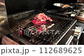 日本一家餐廳的廚房裡，一名廚師正在木炭上烤雞肉。 112689625