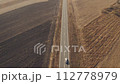 Aerial drone footage of cars and trucks on the road through plain countryside landscape on sunny autumn day 112778979