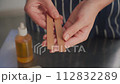 The creative process of making wax scented candles. Female hands hold wooden candle wicks.Close up. 112832289