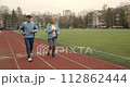Couple old men running marathon stadium arena. Grandparent jog together. Romantic elderly smiling people sport training. Granny and Grandpa workout. Love athletes. Active senior lifestyle. Health care 112862444