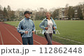 Couple old men running marathon stadium arena. Grandparent jog together. Romantic elderly smiling people sport training. Granny and Grandpa workout. Love athletes. Active senior lifestyle. Health care 112862448
