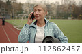 Mature adult woman practicing fitness outdoors holding yoga mat. Sports for elderly people. 112862457
