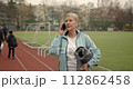 Mature adult woman practicing fitness outdoors holding yoga mat. Sports for elderly people. 112862458