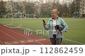 Mature adult woman practicing fitness outdoors holding yoga mat. Sports for elderly people. 112862459