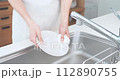 A man wearing an apron washing dishes in the kitchen 112890755