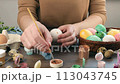 Women's hands paint Easter eggs with paints of different colors. Watercolor painting on eggs. 113043745