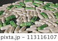 A man takes a green capsule from a multitude of capsules. 113116107