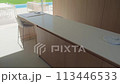 Contemporary kitchen with island, stools, white countertop, and pool view 113446533