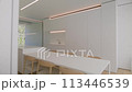Dining room features long white table and chairs with hardwood flooring 113446539