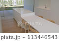 A building with a long white table and chairs made of wood 113446543