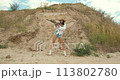 Beautiful young woman holding a shotgun on a field 113802780