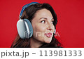 Brunette mature woman listening music with headphones,red studio.wireless player 113981333