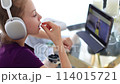 Girl with headphones uses tablet computer while eating blueberries 114015721