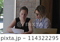Two businesswomen sit discussion over financial report. Commitment to success analyze of financial report numbers and strategize for future growth finding fulfillment in endeavors financial report. 114322295