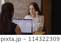 Two women sit at table with laptop engaged in lively business discussion. Business discussion cooperation in business endeavors emphasizing importance of collaboration and synergy discussion. 114322309