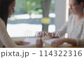 Two businesswomen sit at table paperwork handling documents. Pen in hand women annotate papers embodying essence of meticulous document management in business operations Paperwork documents. 114322316