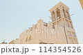 House in traditional Arabic architecture with wind tower. Traditional Arabic style building with windcatcher tower and palm leaves thatched roof. Old Dubai, UAE. Sounds call to prayer in Arabian city 114354526