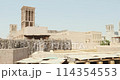 House in traditional Arabic architecture with wind tower. Traditional Arabic style building with windcatcher tower and palm leaves thatched roof. Old Dubai, UAE. View of rooftops of old Arab city 114354553